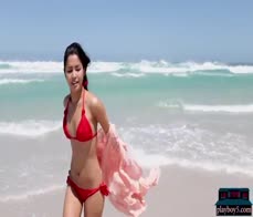 Petite Asian MILF model Chloe Rose gives a bikini striptease on the beach